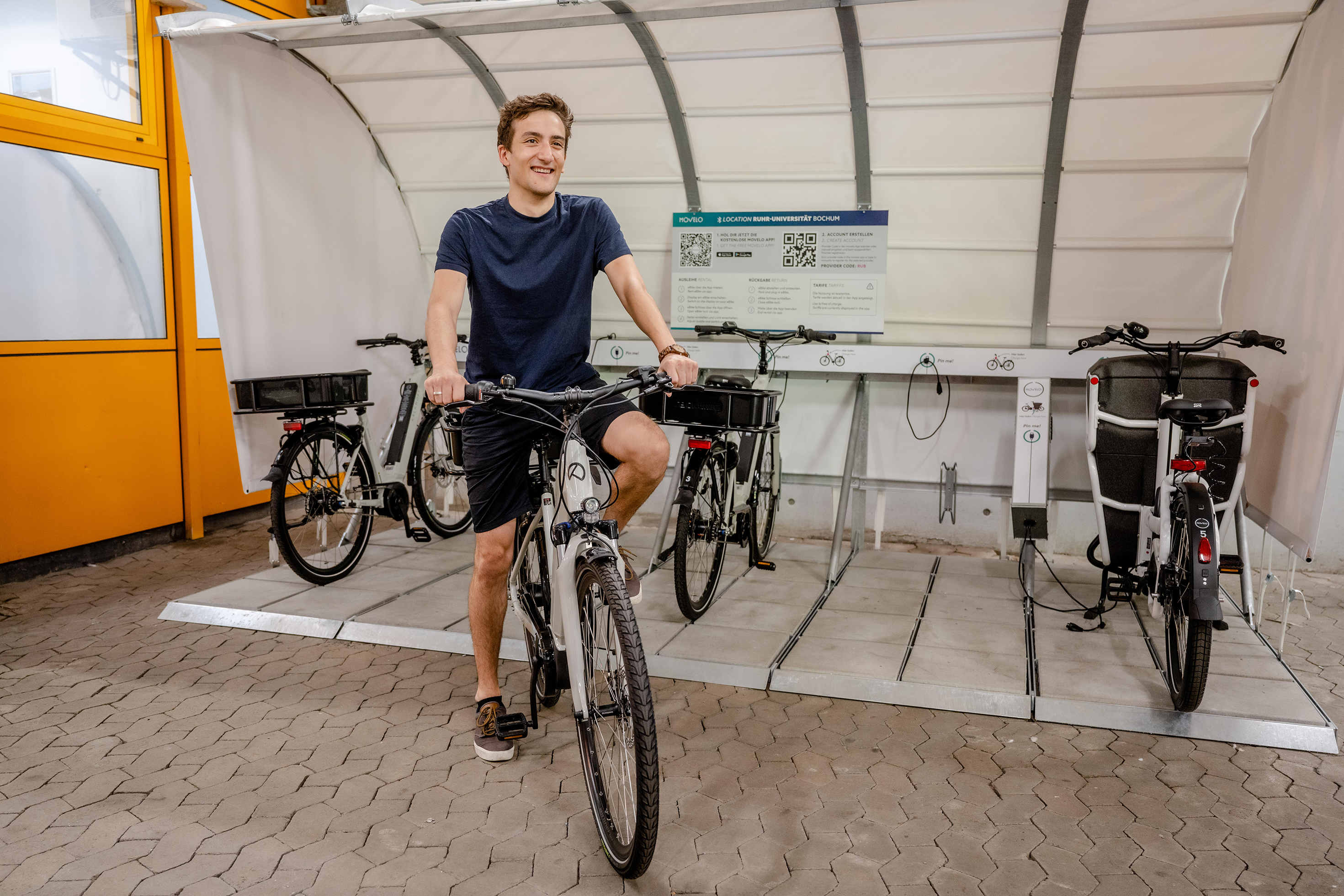 Foto: Männliche Person testet eines der E-Bikes für Dienstgänge auf dem Campus der Ruhr-Universität Bochum