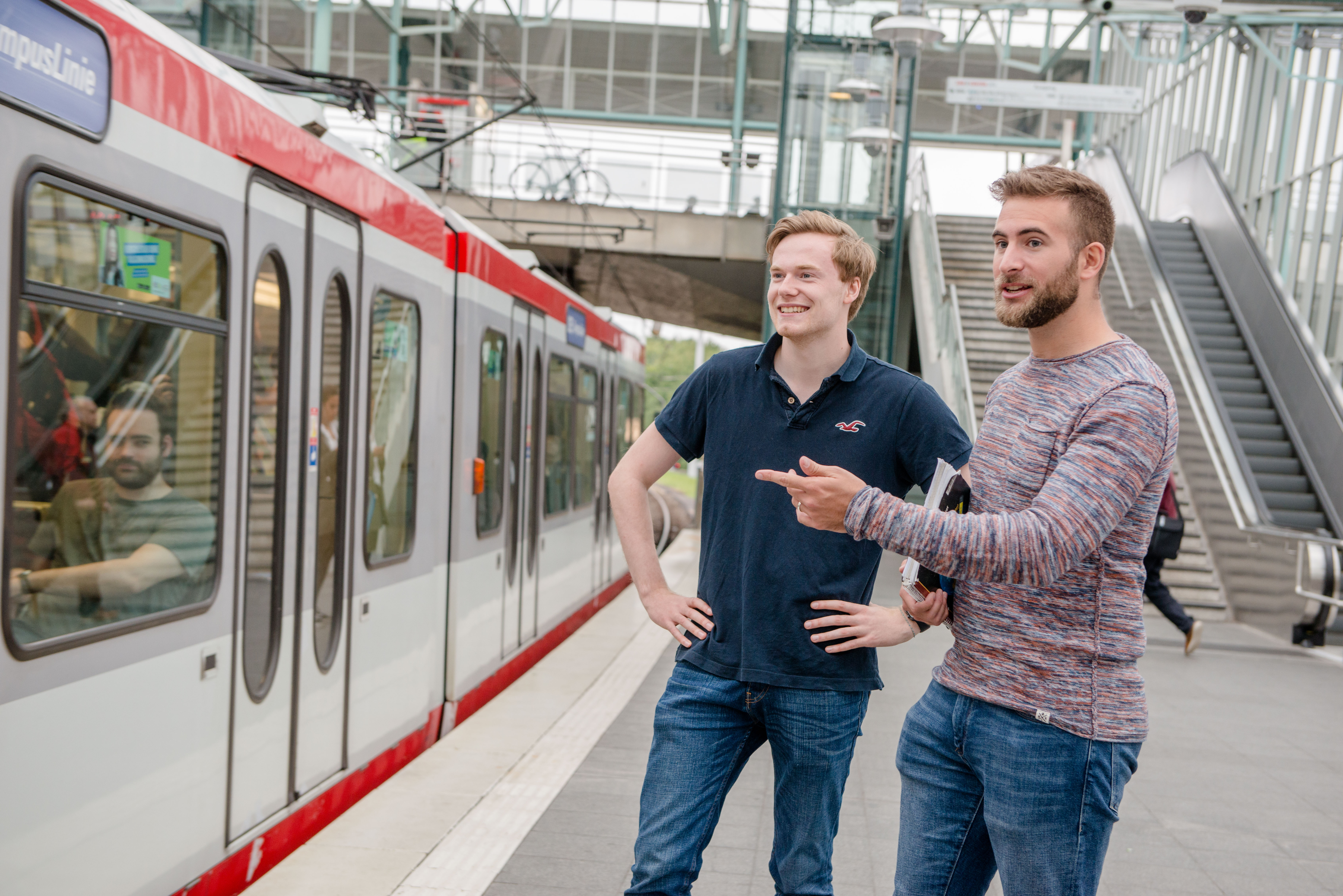 Foto: Zwei Studenten erwarten die gerade einfahrende U35 Linie. 