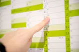 Ausschnitt von einem Wandkalender; ein Finger zeigt auf einen konkreten Tag