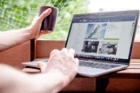 Arbeiten am Laptop am Newsportal auf dem Balkon