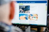 Eine Person schaut auf einen Bildschirm, auf dem das Newsportal der Ruhr-Universität Bochum zu sehen ist.