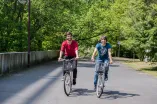 Zwei Studierende fahren Fahrrad auf dem Campus.