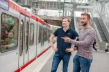 Foto: Zwei Studenten erwarten die gerade einfahrende U35 Linie. 