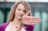 Foto: Eine Frau hält ihre flache Hand in die Kamera. Auf ihrer Handfläche steht in roten Großbuchstaben das Wort "Stop". Die Hand ist im Vordergrund, das Gesicht der Frau ist im Hintergrund und etwas unscharf.