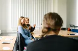 Foto: Drei Personen sitzen zusammen, lächeln und sprechen miteinander.