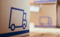 Foto: Umzugskarton auf Holzboden in Nahaufnahme.