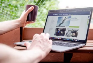 Arbeiten am Laptop am Newsportal auf dem Balkon