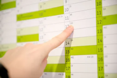 Ausschnitt von einem Wandkalender; ein Finger zeigt auf einen konkreten Tag