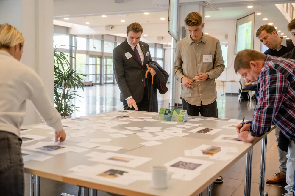 Teilnehmende arbeiten an einer Themenstation, bei welcher sie Fotos auswählen und beschriften