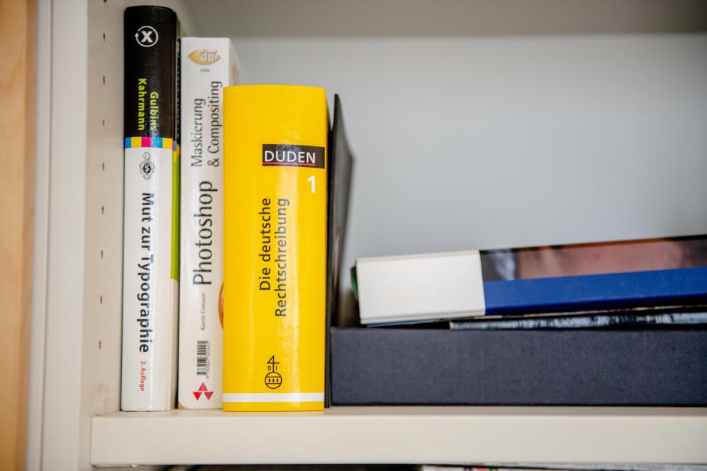 Bücher in einem Regal, unter anderem Die deutsche Rechtschreibung des Duden-Verlags