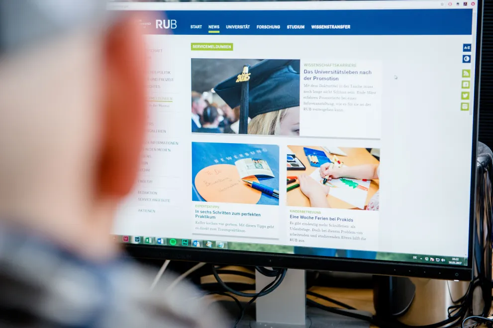 Eine Person schaut auf einen Bildschirm, auf dem das Newsportal der Ruhr-Universität Bochum zu sehen ist.