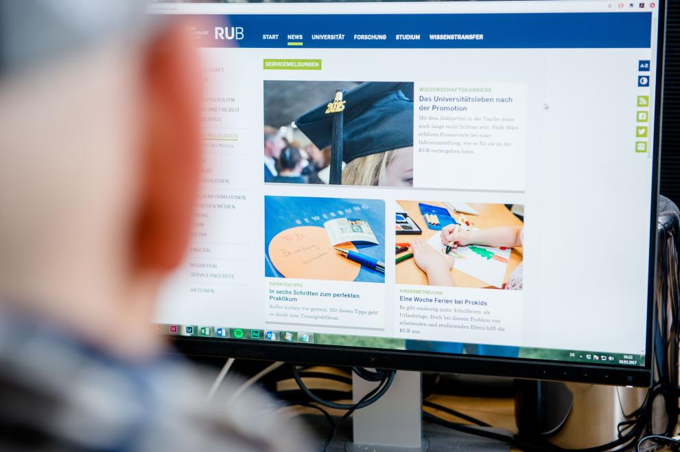 Eine Person schaut auf einen Bildschirm, auf dem das Newsportal der Ruhr-Universität Bochum zu sehen ist.