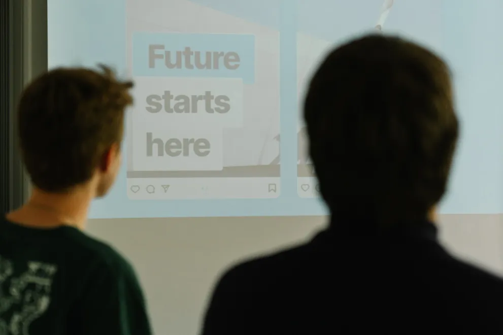 Foto: Zwei Personen schauen auf eine Leinwand, auf der steht "Future starts here".