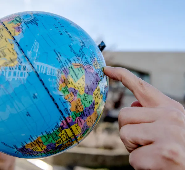 Ein Finger zeigt auf einen Globus, im Hintergrund die RUB